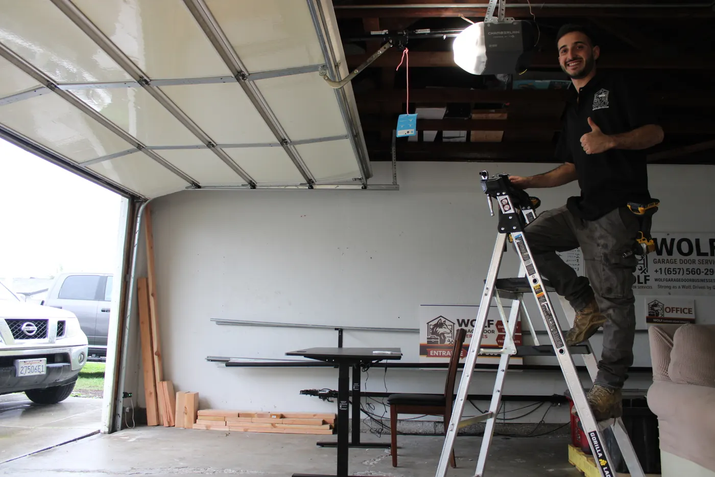 Technician on a ladder finishing a garage door opener install