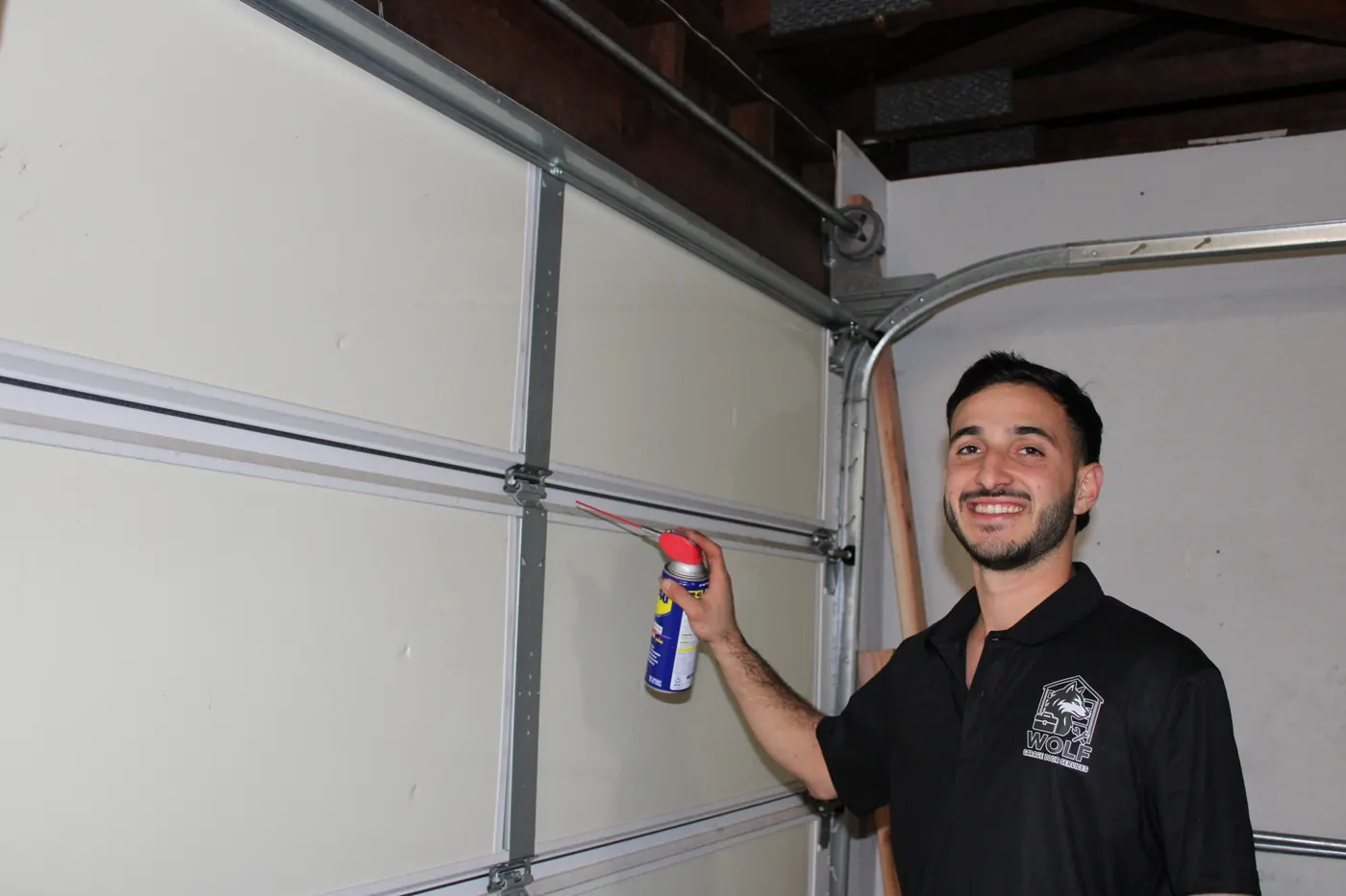 Wolf technician lubricating garage door hinges and rollers
