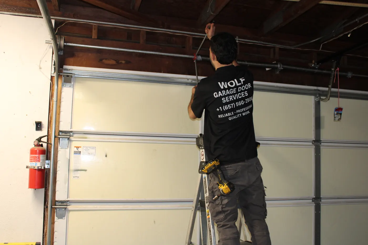 Technician on a ladder adjusting the track of a garage door